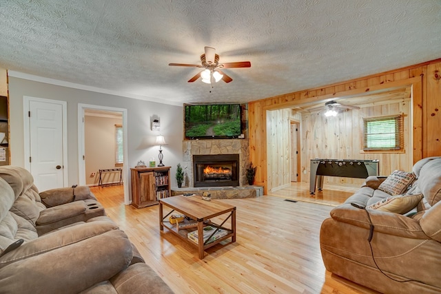 living room with a fireplace, wood-type flooring, ceiling fan, and wooden walls