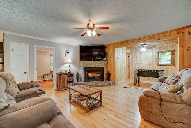 living room with hardwood / wood-style flooring, wood walls, crown molding, and a fireplace