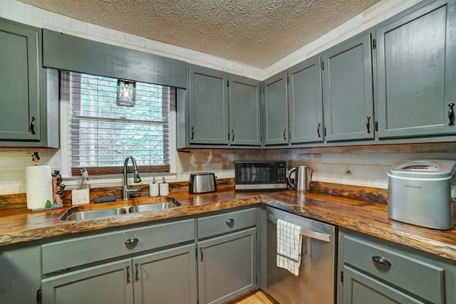 kitchen with stainless steel dishwasher, sink, and a textured ceiling