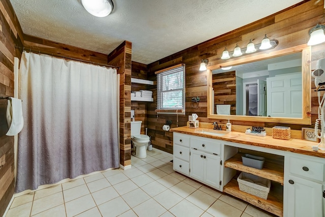 bathroom featuring tile patterned floors, vanity, a textured ceiling, toilet, and wood walls