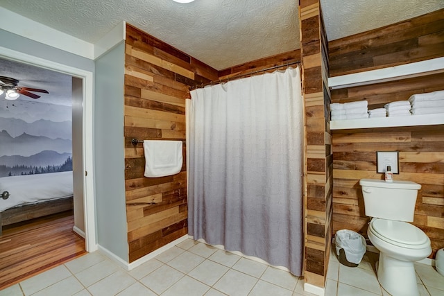 bathroom featuring tile patterned flooring, toilet, ceiling fan, and wood walls