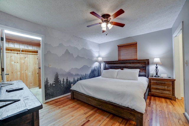 bedroom featuring ceiling fan, light wood-type flooring, and a textured ceiling