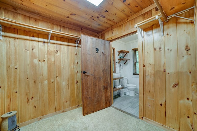 interior space featuring connected bathroom and wooden walls