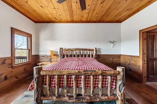 bedroom featuring hardwood / wood-style floors, wood walls, crown molding, and a wainscoted wall