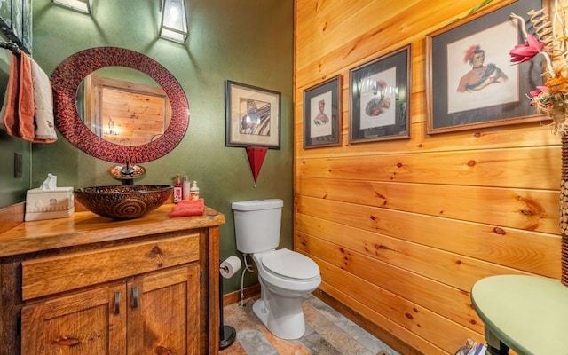 half bath featuring wood walls, toilet, and vanity
