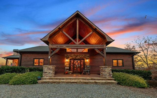 exterior space with roof with shingles, covered porch, and faux log siding