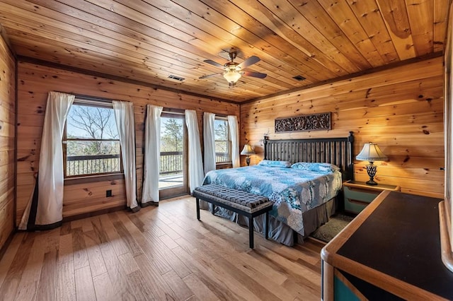 bedroom featuring hardwood / wood-style floors, access to exterior, wooden walls, and visible vents
