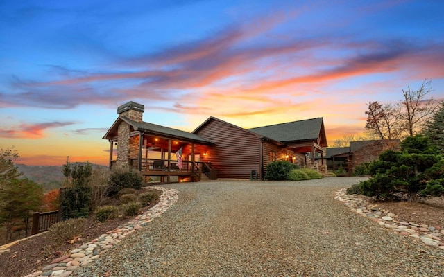 view of property exterior with a chimney, stone siding, and gravel driveway