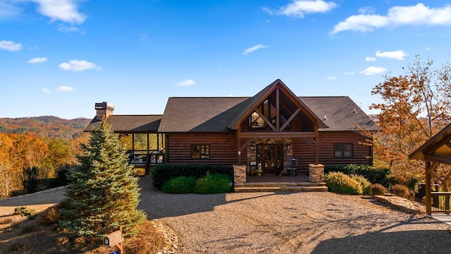 view of front of home with log exterior, a chimney, and covered porch