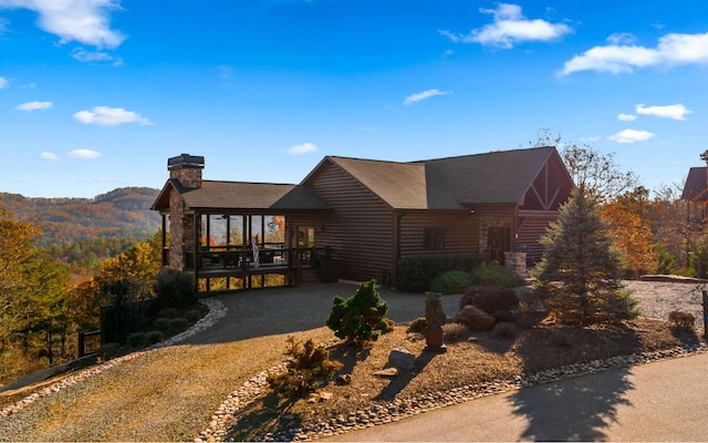 view of front of property with a shingled roof, driveway, and a chimney