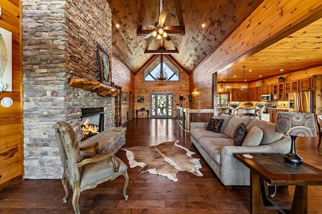 living room with ceiling fan, a fireplace, dark wood finished floors, high vaulted ceiling, and wood walls