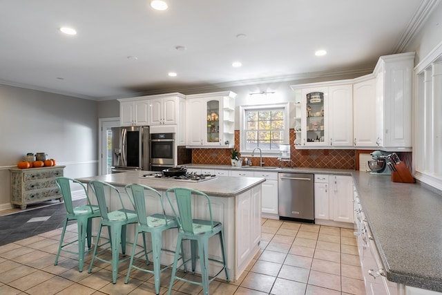 kitchen featuring tasteful backsplash, stainless steel appliances, a kitchen bar, a sink, and white cabinetry