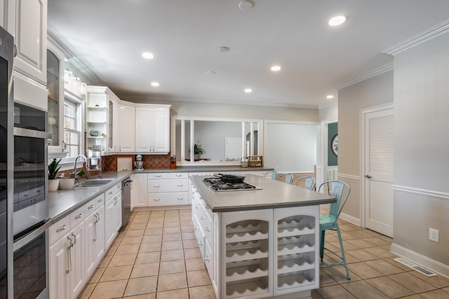 kitchen featuring a breakfast bar area, appliances with stainless steel finishes, ornamental molding, a sink, and light tile patterned flooring