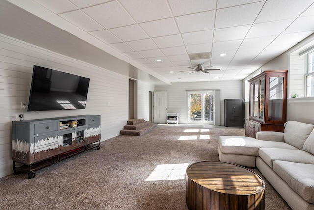 living area featuring a drop ceiling, a ceiling fan, carpet flooring, and a wealth of natural light