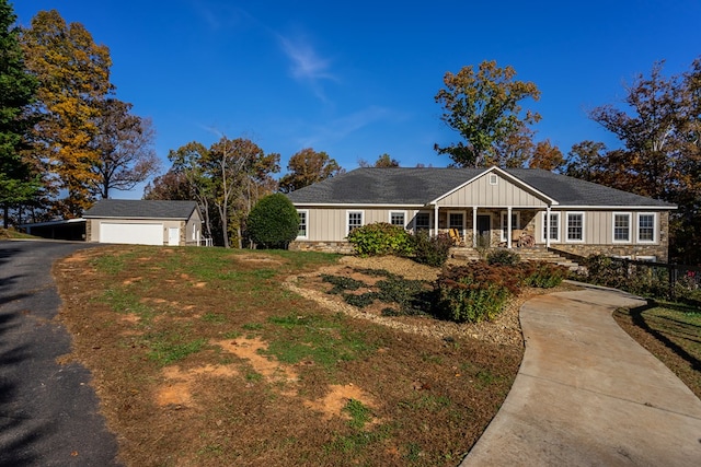 ranch-style house featuring a porch, a front lawn, driveway, stone siding, and board and batten siding