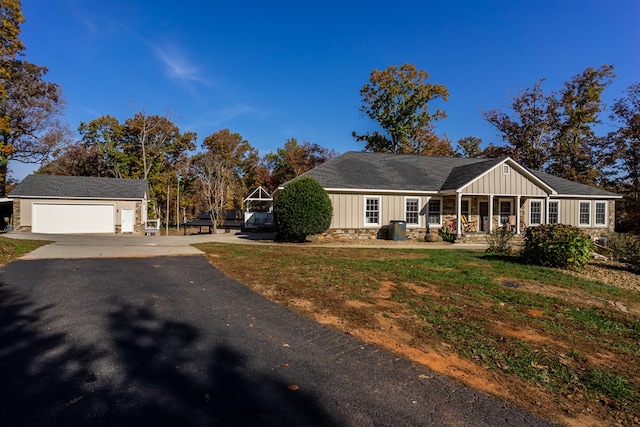 view of front of property with board and batten siding, an outdoor structure, a porch, driveway, and stone siding