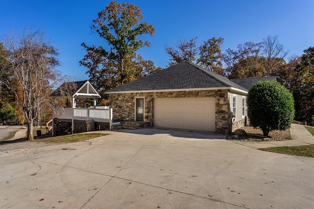 view of front of home featuring a garage, a shingled roof, concrete driveway, and stone siding