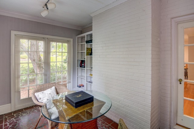dining area with crown molding, brick wall, baseboards, and brick floor
