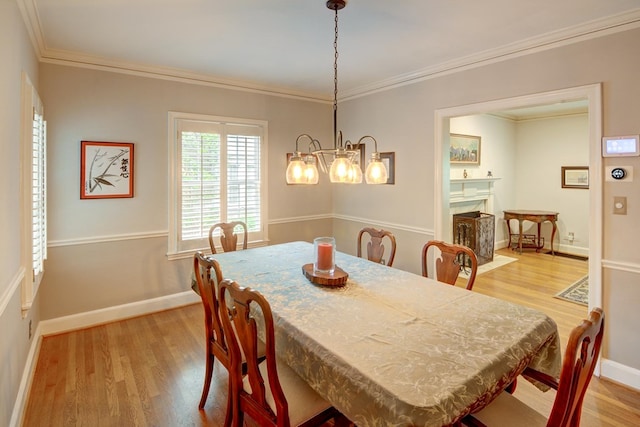 dining space with crown molding, light wood-style flooring, baseboards, and a notable chandelier
