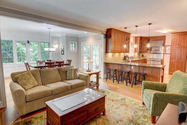 living room featuring ornamental molding, light wood-style flooring, and a healthy amount of sunlight
