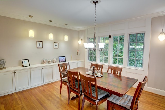 dining room featuring crown molding, a notable chandelier, and light wood finished floors