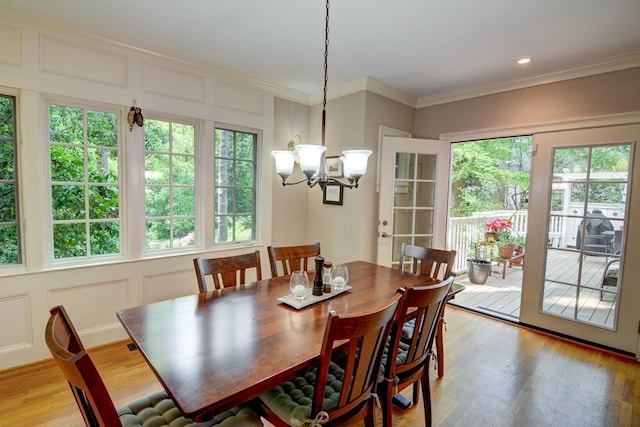 dining space with an inviting chandelier, a decorative wall, and a healthy amount of sunlight