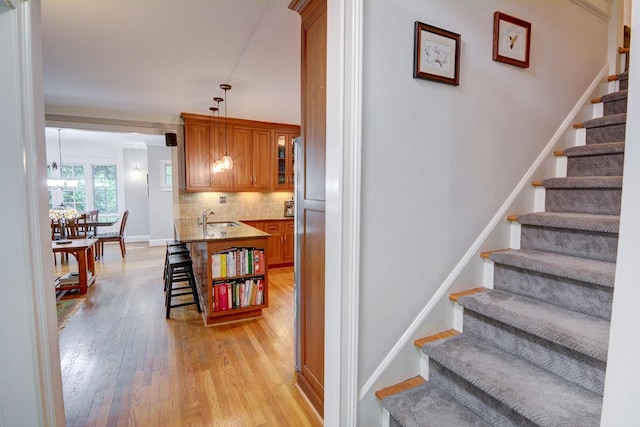 stairway featuring baseboards, an inviting chandelier, and wood finished floors