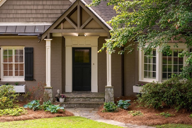 view of exterior entry with brick siding and a standing seam roof