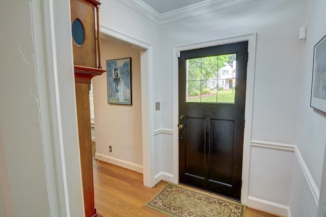 foyer entrance with crown molding, baseboards, and light wood-type flooring
