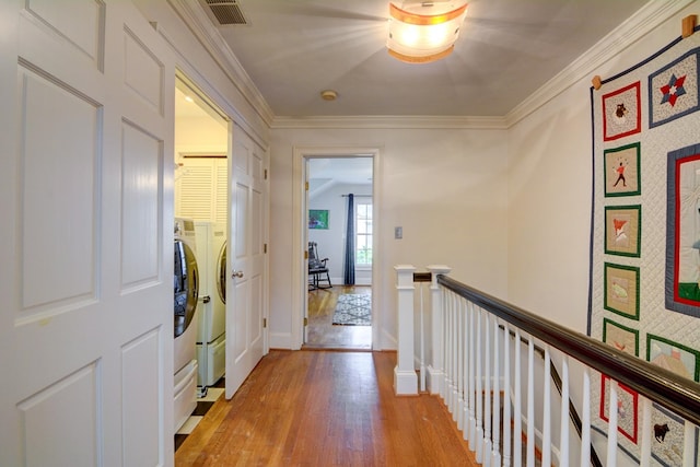 corridor featuring visible vents, crown molding, baseboards, light wood finished floors, and an upstairs landing