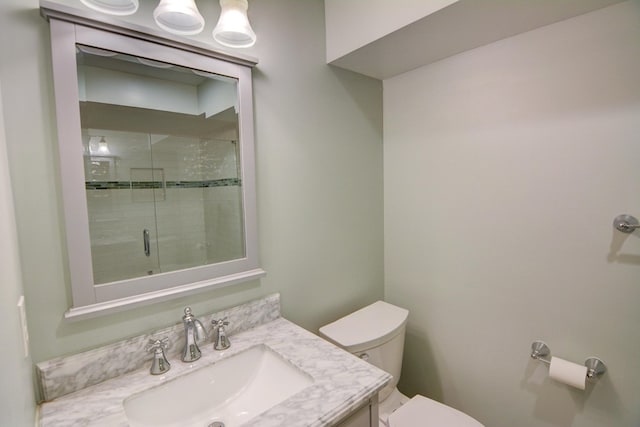 bathroom featuring vanity, a tile shower, and toilet