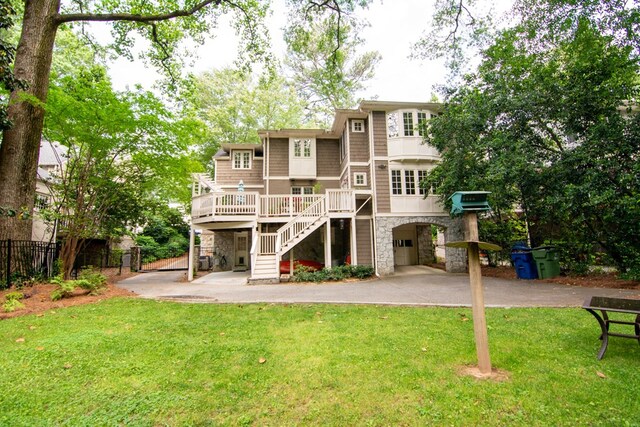 back of house with stairway, a yard, fence, and stone siding