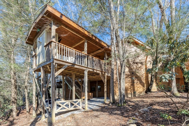 back of property with a deck, a carport, and stairway