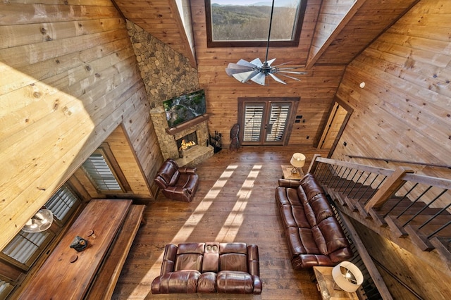 unfurnished living room featuring high vaulted ceiling, a stone fireplace, wood walls, and wooden ceiling