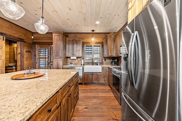 kitchen with decorative light fixtures, wooden ceiling, appliances with stainless steel finishes, and wood walls