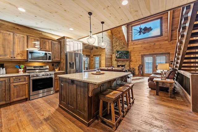 kitchen featuring pendant lighting, appliances with stainless steel finishes, wooden walls, high vaulted ceiling, and wooden ceiling