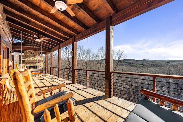 wooden terrace featuring ceiling fan and an outdoor stone fireplace