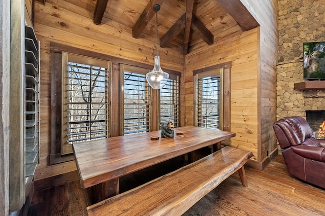 dining area with hardwood / wood-style floors, wood ceiling, wood walls, and beamed ceiling