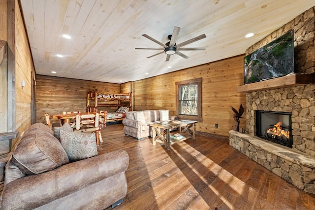 living room featuring hardwood / wood-style flooring, wooden walls, wooden ceiling, ceiling fan, and a fireplace