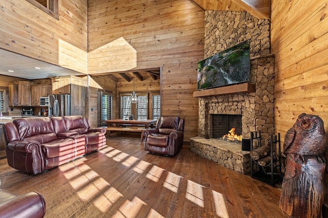 living room with high vaulted ceiling, hardwood / wood-style floors, wood walls, and a fireplace