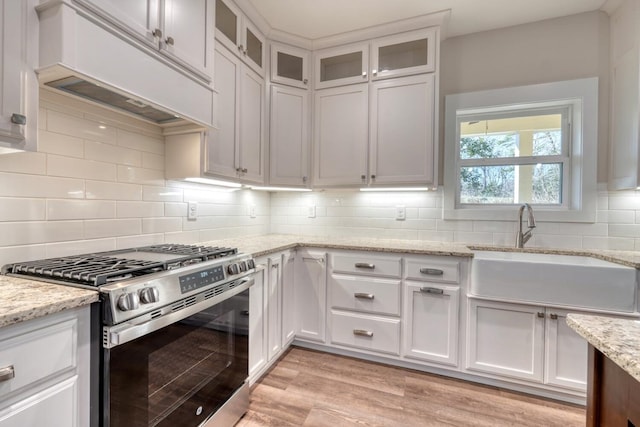 kitchen with gas range, white cabinets, and custom exhaust hood