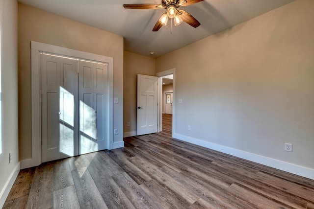 unfurnished bedroom with wood-type flooring, a closet, and ceiling fan