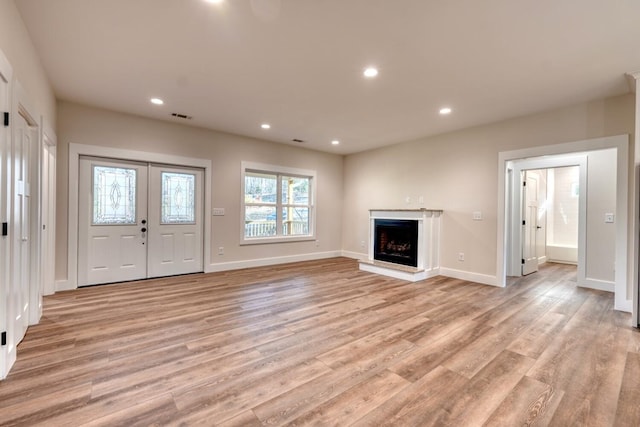 unfurnished living room featuring light hardwood / wood-style flooring and french doors