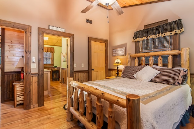 bedroom featuring ceiling fan, light hardwood / wood-style flooring, wood ceiling, and wooden walls