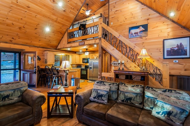 living room with ceiling fan, wood ceiling, wood walls, and light hardwood / wood-style floors