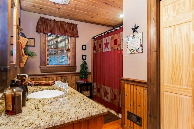 bathroom with vanity, wood walls, and wooden ceiling