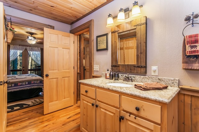 bathroom featuring ceiling fan, vanity, wood-type flooring, and wood ceiling