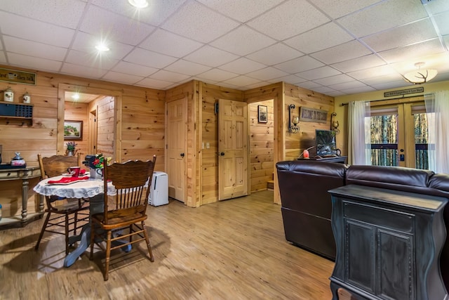 dining area with a drop ceiling, hardwood / wood-style floors, and wooden walls