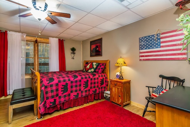 bedroom featuring ceiling fan, light hardwood / wood-style floors, and a paneled ceiling