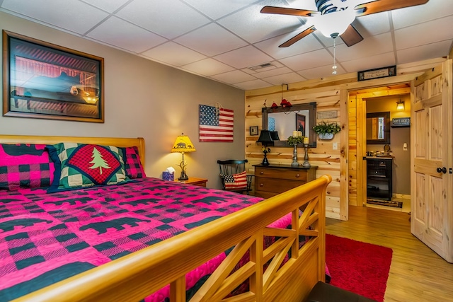 bedroom featuring ceiling fan, a drop ceiling, and hardwood / wood-style floors